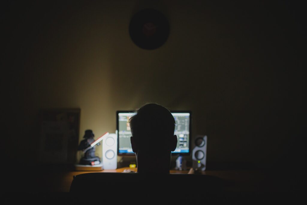 Teenager sitting at computer in the dark.