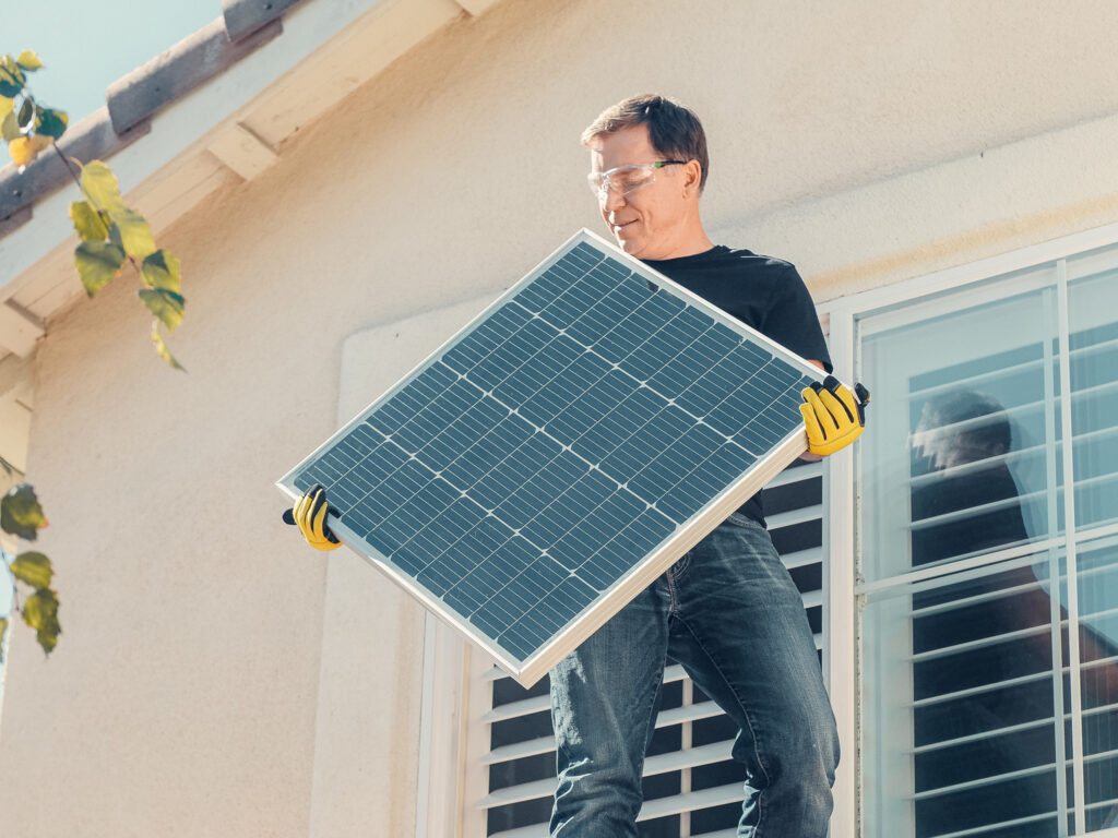 Person installing solar panel on home
