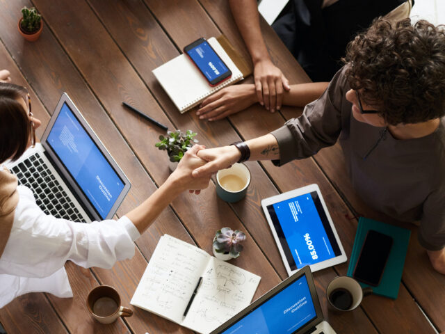 group of people with computers comparing notes at table