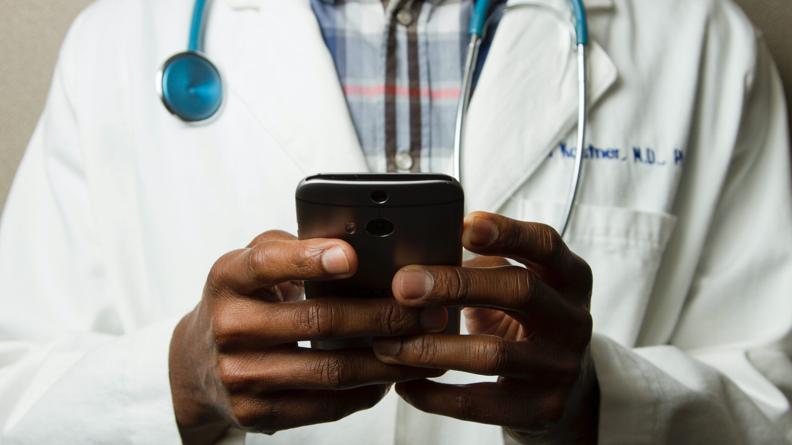 Doctor holding mobile phone in hands viewing patient data