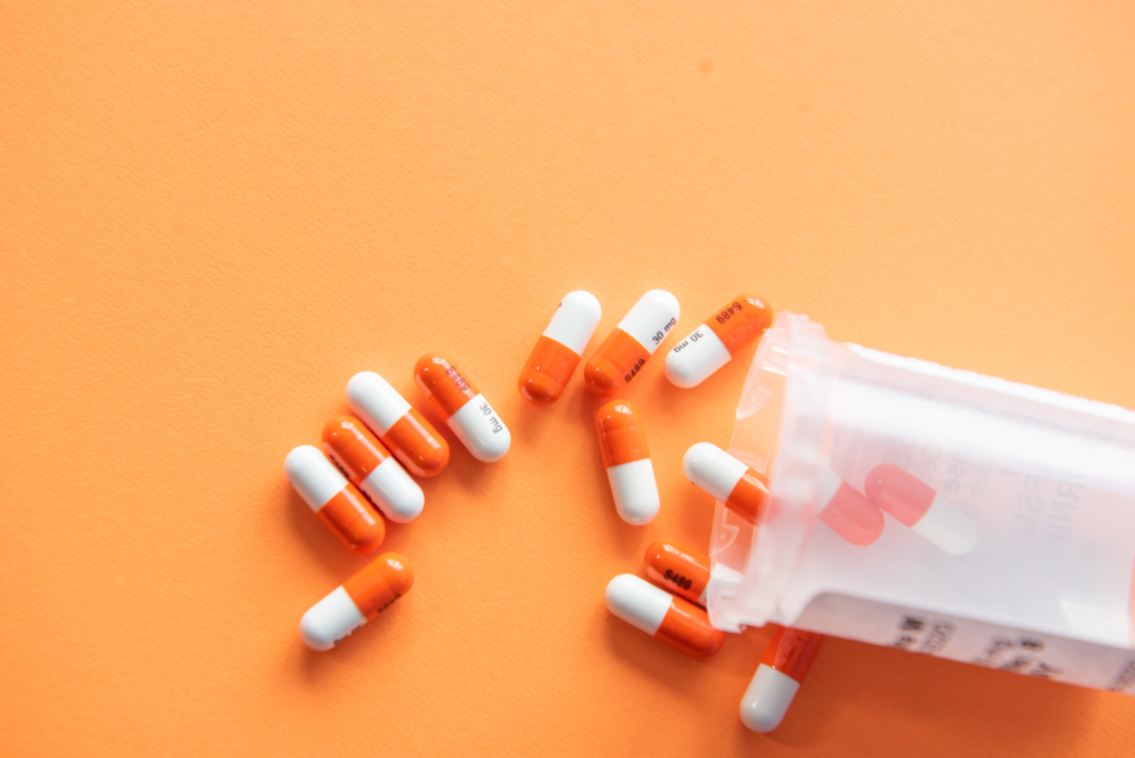 Pharmacy pills spilled on orange background